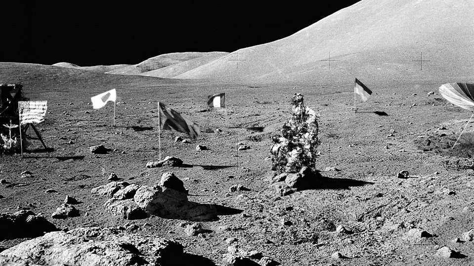Black-and-white photograph of the dry, rocky environment planted with various national flags