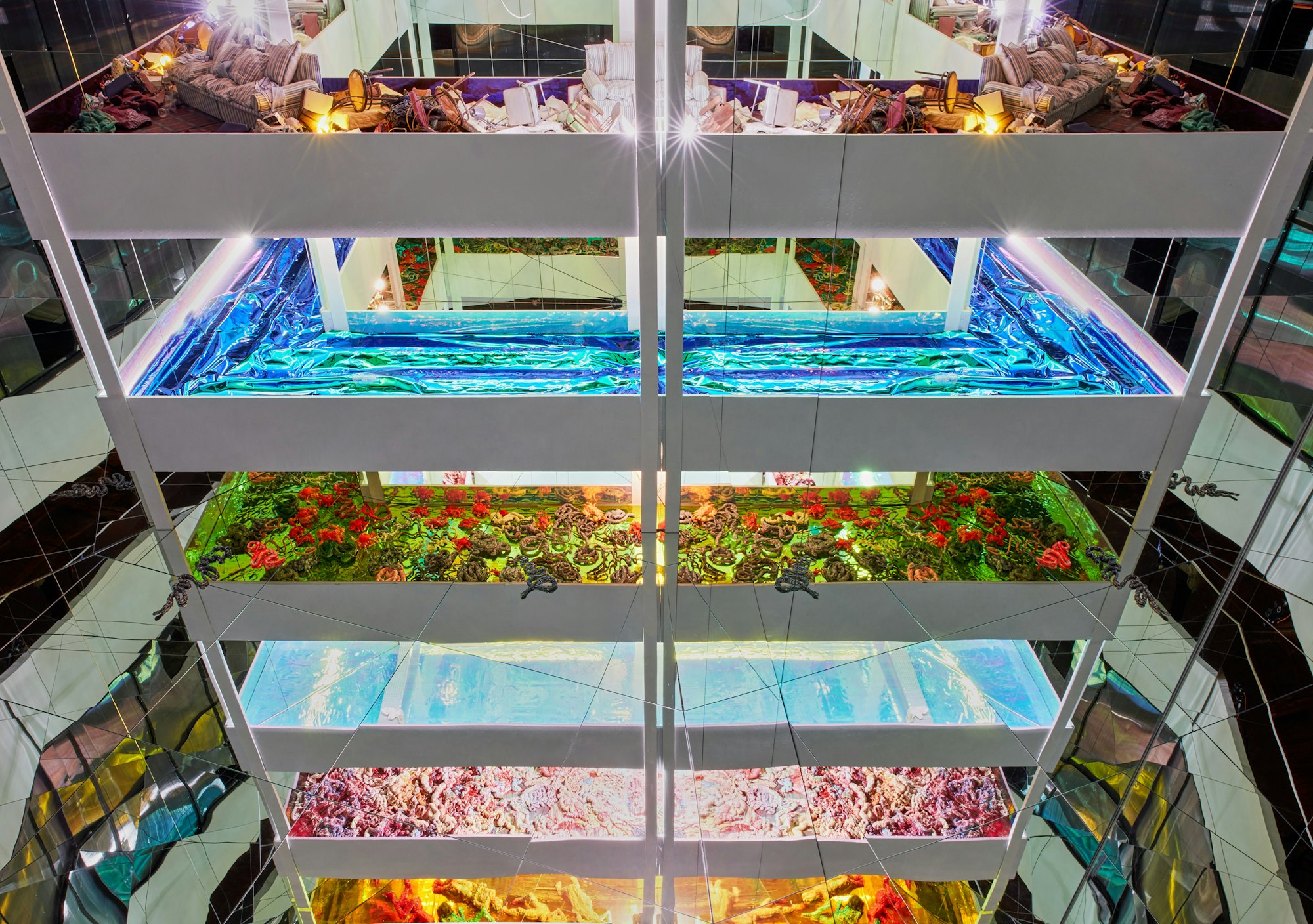 The atrium in a mult-levelled building in which each level is filled with different highly coloured objects and materials