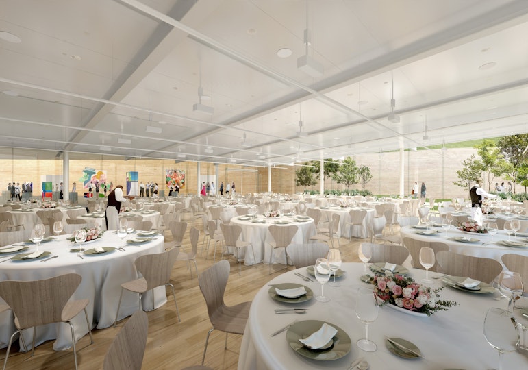 Large indoor space with round cloth-covered tables plus chairs and views into a garden and gallery space