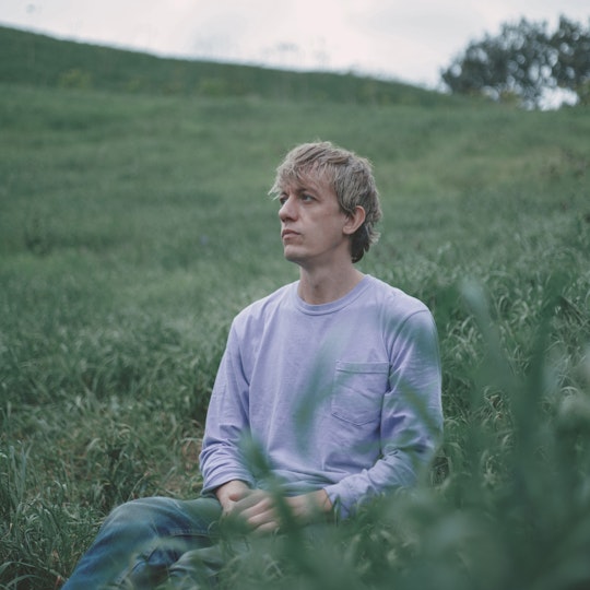 A person sits on a grassy hillside