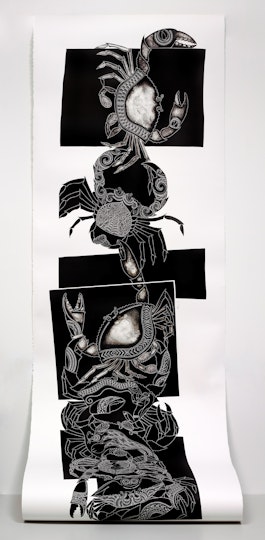 A long strip of white paper, with black-and-white illustrations of crabs, unfurls from a wall