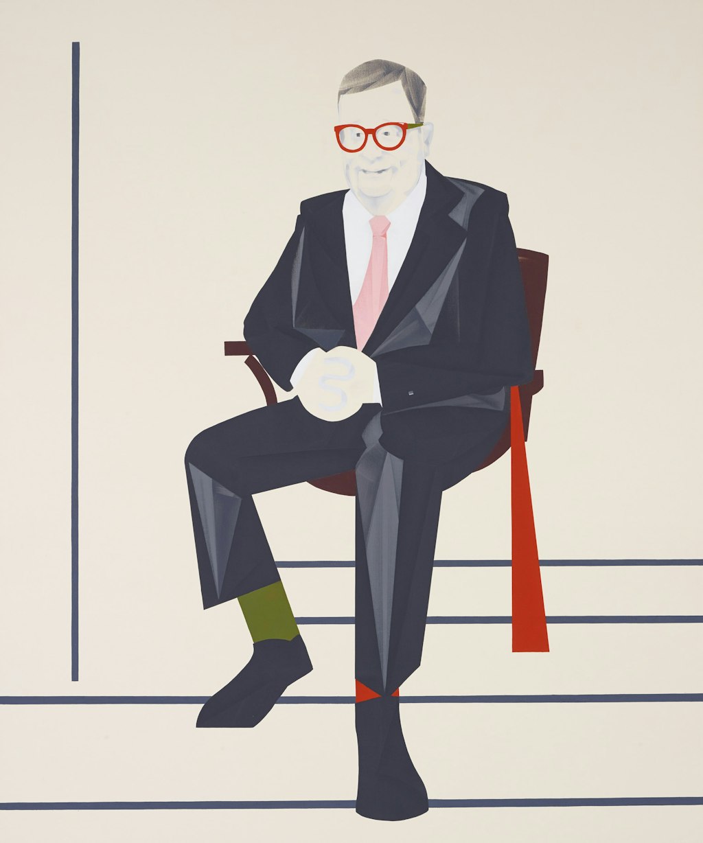 A person sitting in a chair, wearing a dark suit, white shirt, pink tie, one green sock, one red sock and red glasses