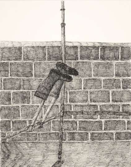 A pair of gumboots hang upside down on construction piping in front of a brick wall