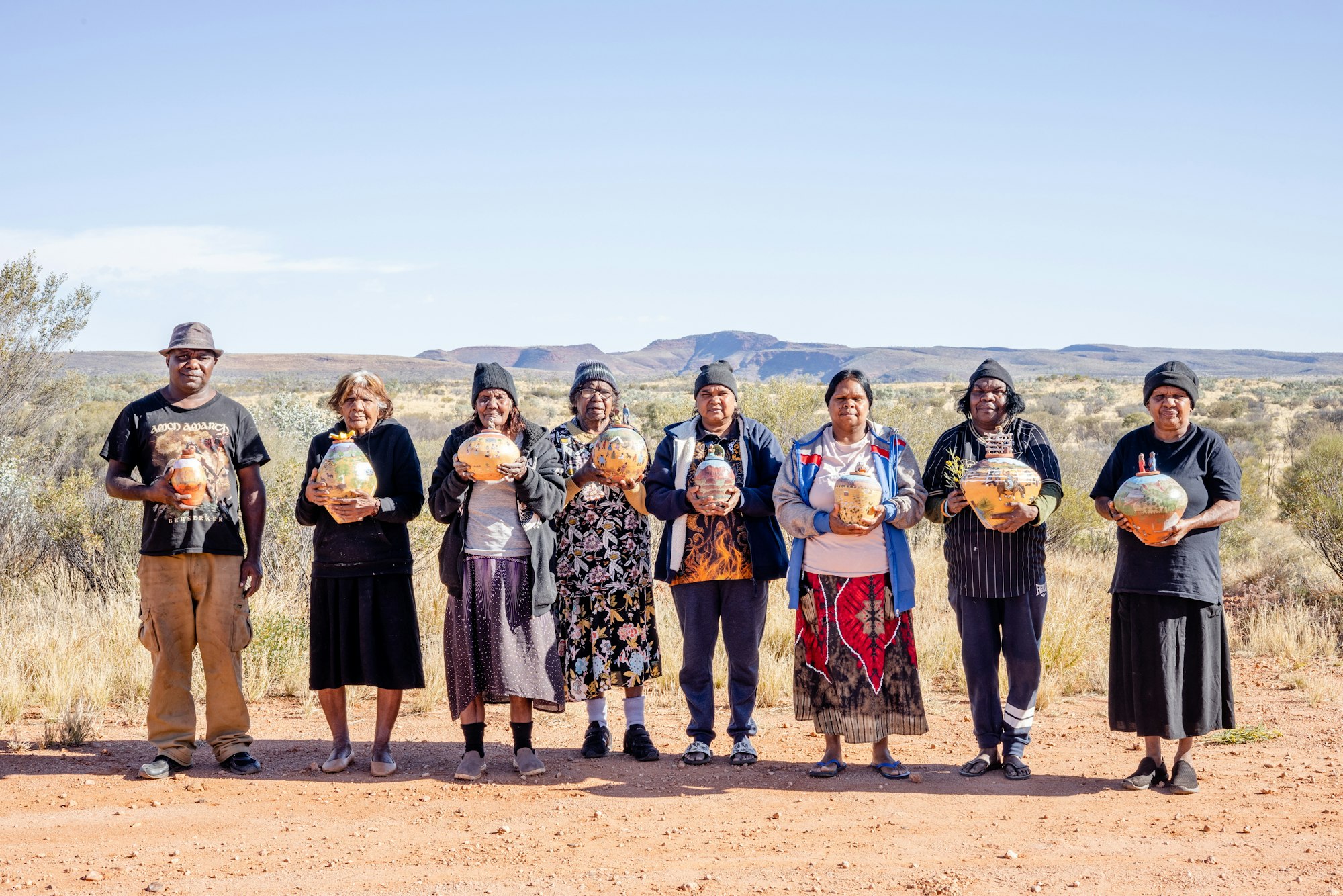 Hermannsburg Potters with their artworks; (from left) Abel Pareroultja, Anita Ratara, Dawn Wheeler, Judith Inkamala, Beth Inkamala, Andrea Rontji, Rona Rubuntja and Hayley Coulthard, 2022, photo © Art Gallery of New South Wales, Bec Capp