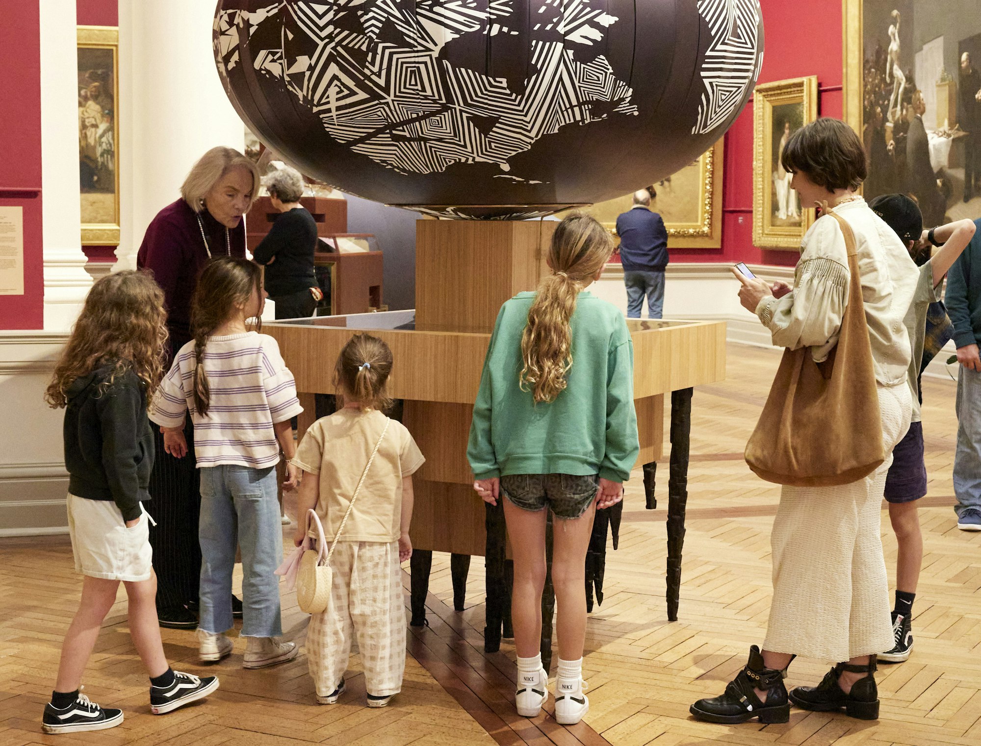 A group of adults and children in a gallery space next to a sculptural installation