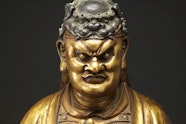 The head and shoulders of a bronze and gold coloured statue