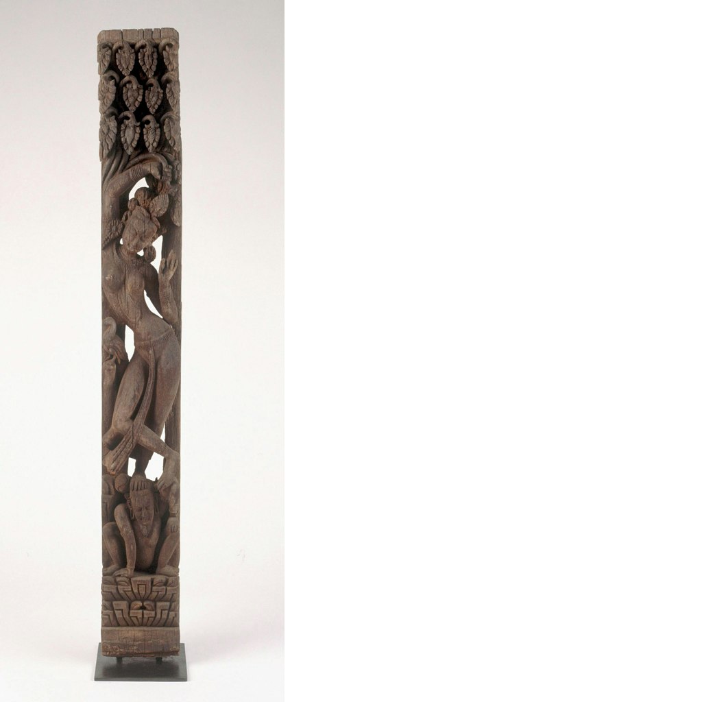 A vertical wooden carving depicting a standing figure, with a small kneeling figure at their feet