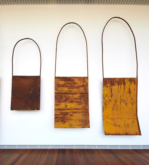 Three metal bag-like objects in different sizes, mounted on a wall