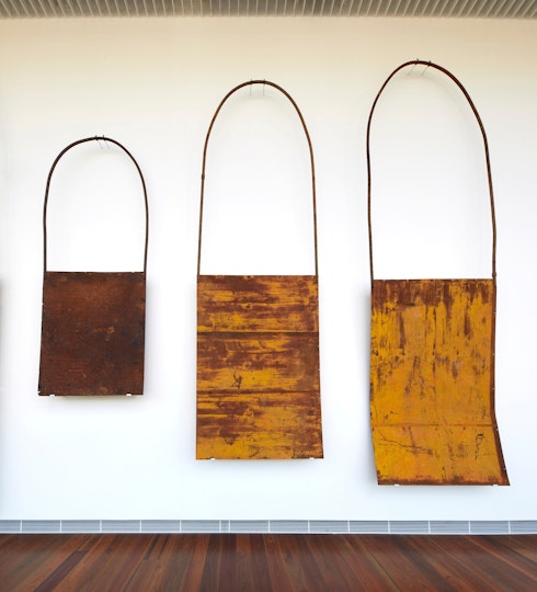 Three metal bag-like objects in different sizes, mounted on a wall