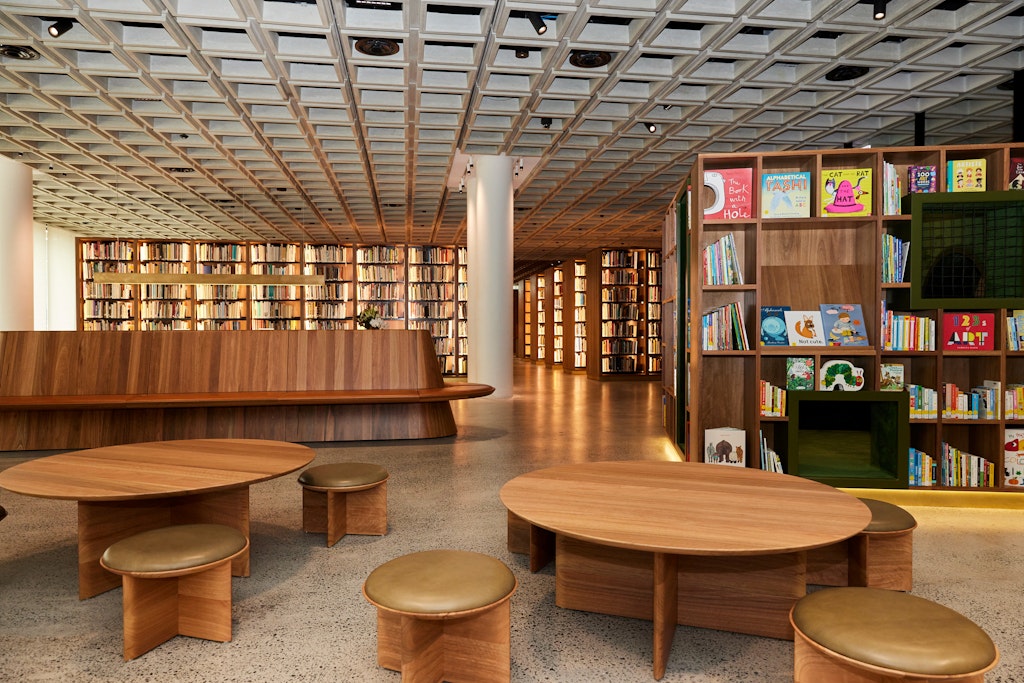 A large space with many rows of books on shelves as well as tables with seating