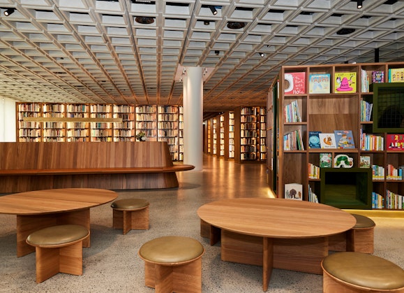 A large space with many rows of books on shelves as well as tables with seating