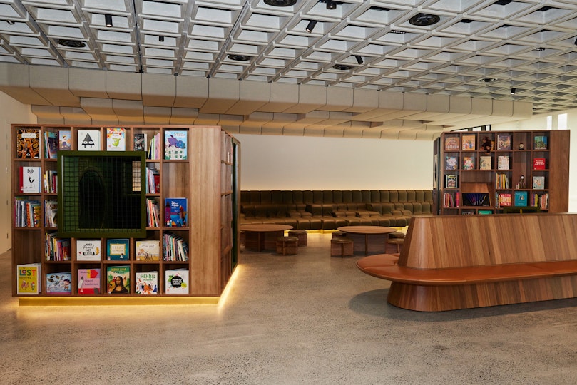 Two multi-sided shelving units holding books in a space with different forms of seating