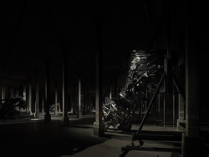 A large sculptural form in a very dark room with columns