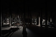 Several large sculptural forms in a very dark room with columns