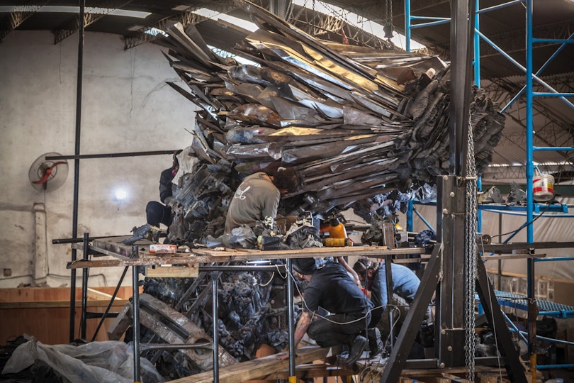 A group of people in a workshop space with a large silver-coloured sculptural form