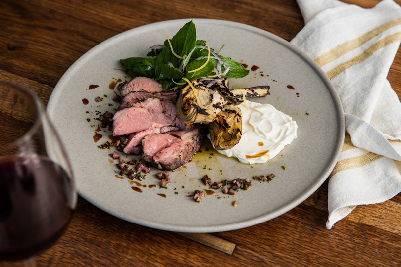 A plate of food, glass of wine and a napkin