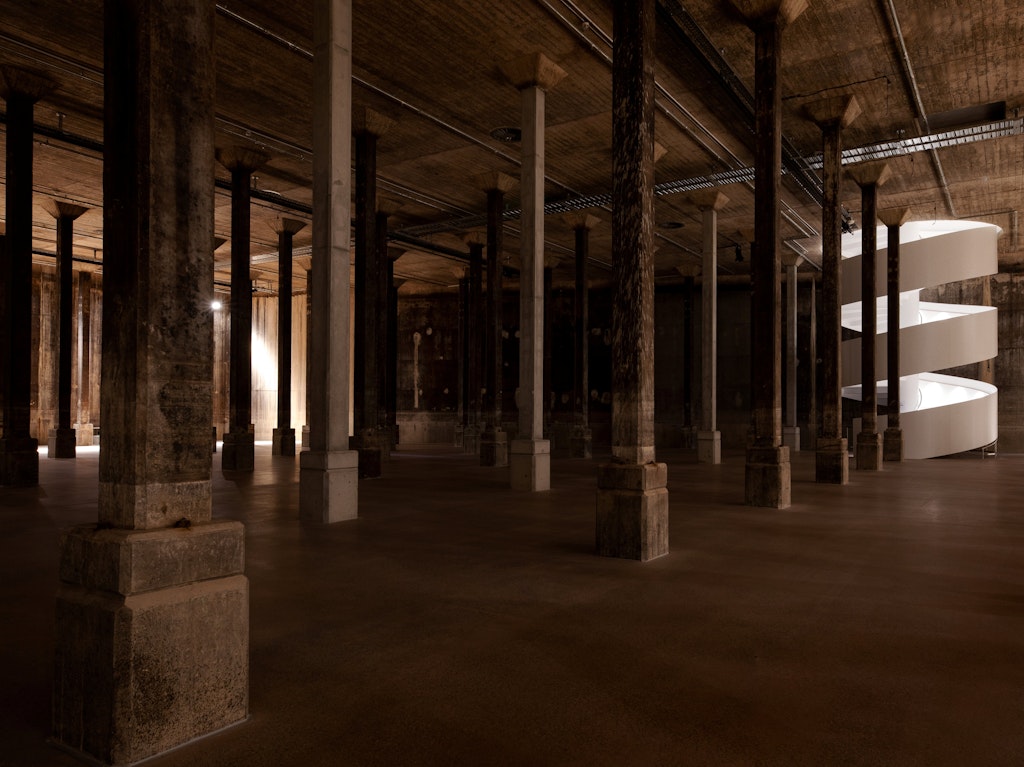 White spiral stairs in a large dark columned space