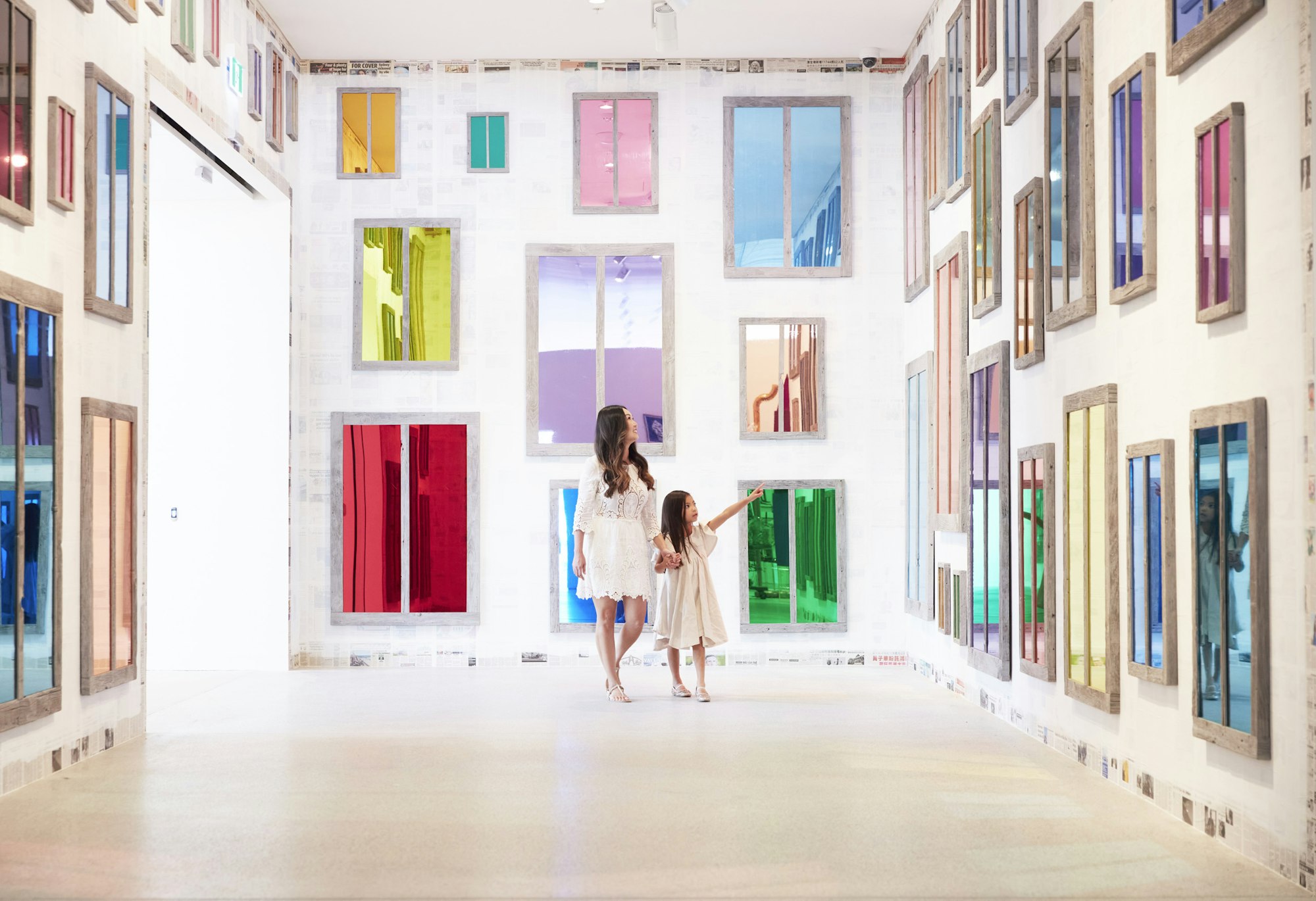 An adult and a child in a room full of coloured mirror-like windows