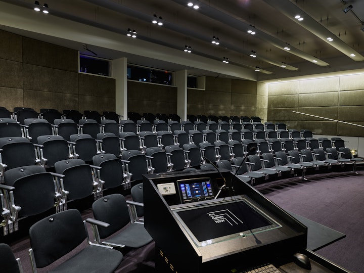 An auditorium with tiered seating and a control panel on a podium