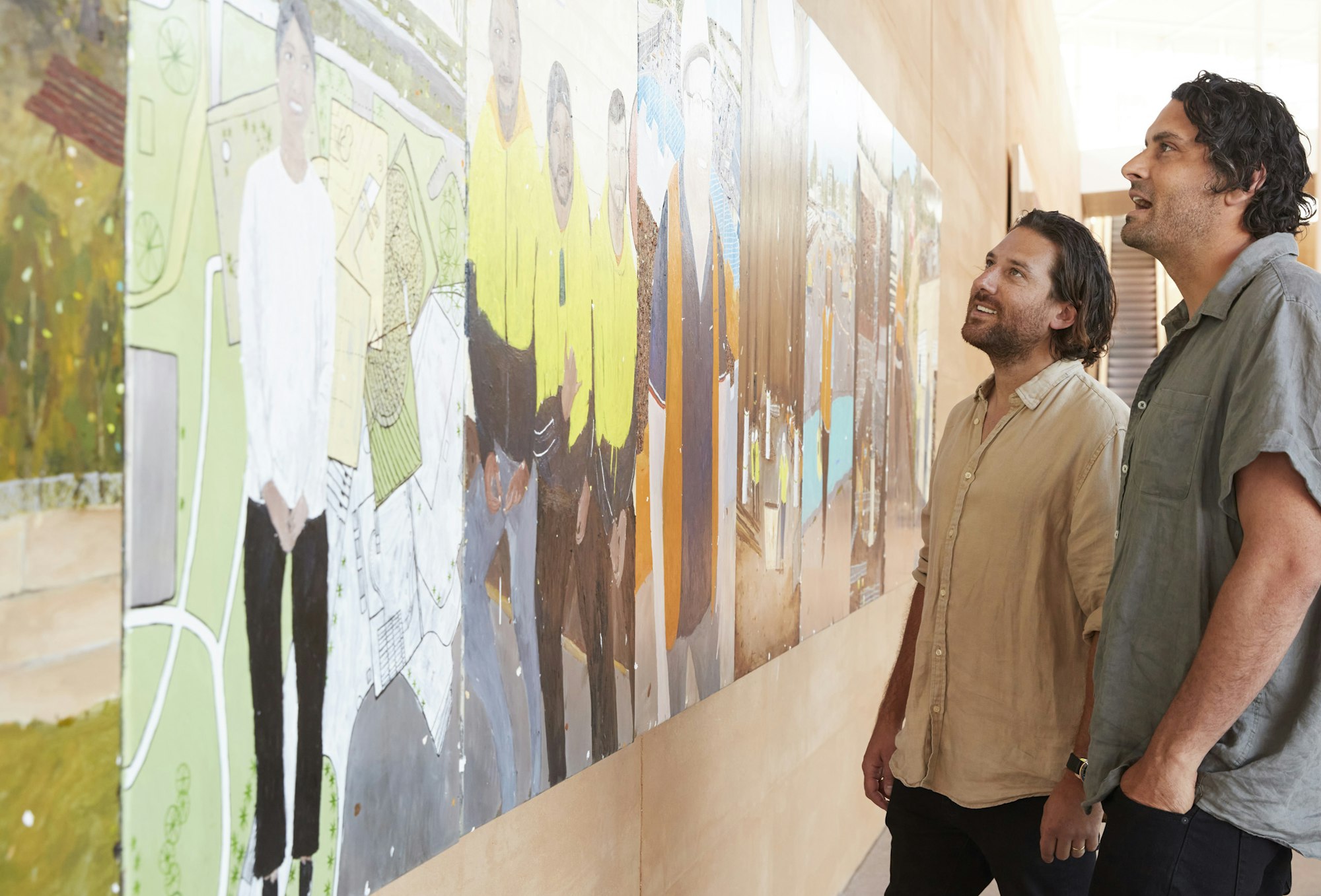 Two people looking at a multi-panel painting on a wall