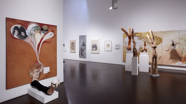 A large room containing paintings, drawings and  wooden sculptures by Brett Whiteley.