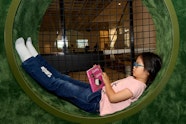 A child lies reading a book in a circular nook