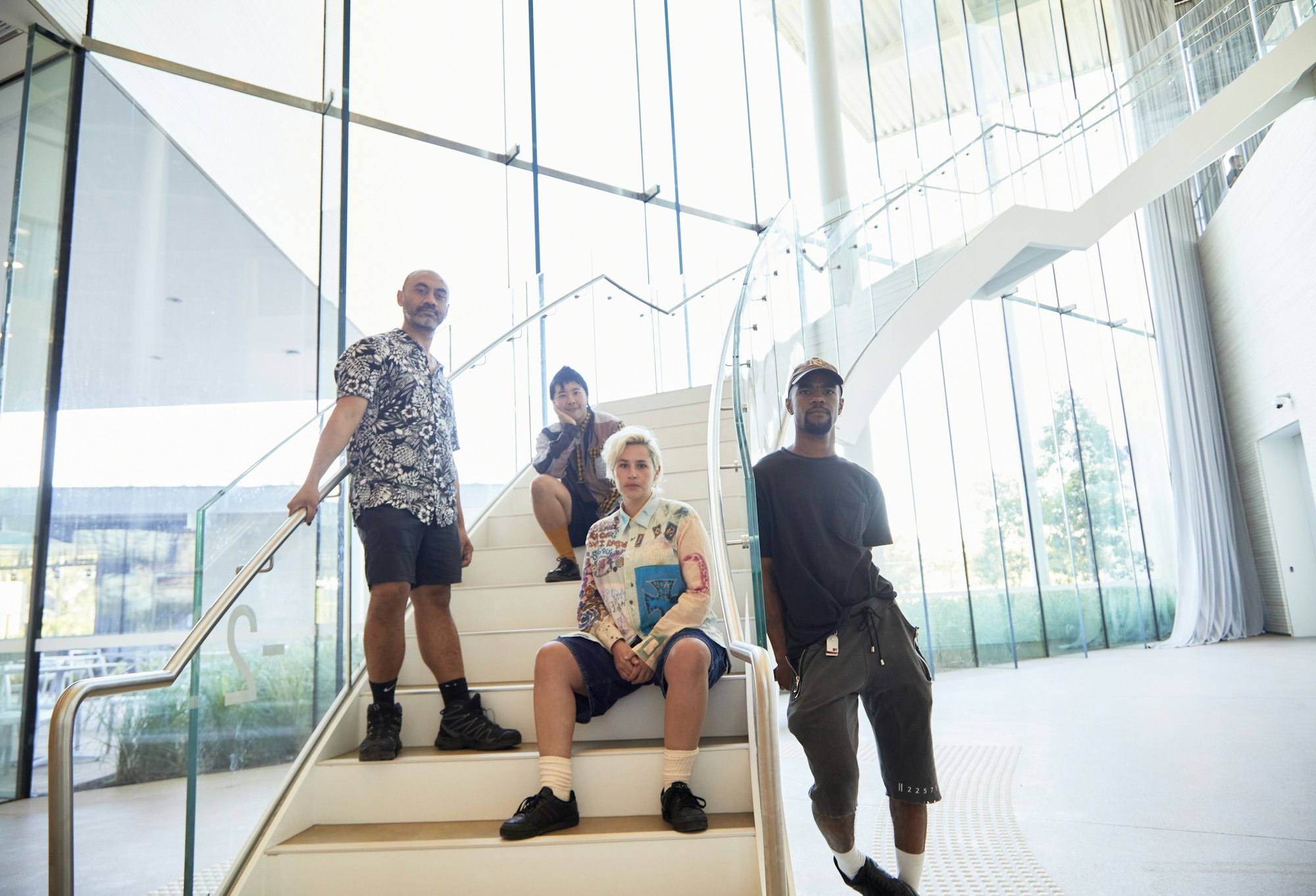 Four people standing and sitting on a staircase, looking directly into the camera.