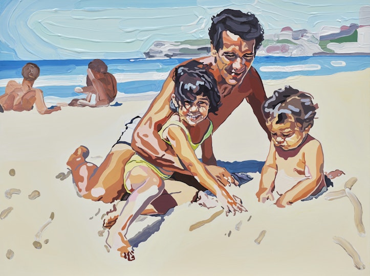 An adult and two children on a beach with two adults reclining in the background