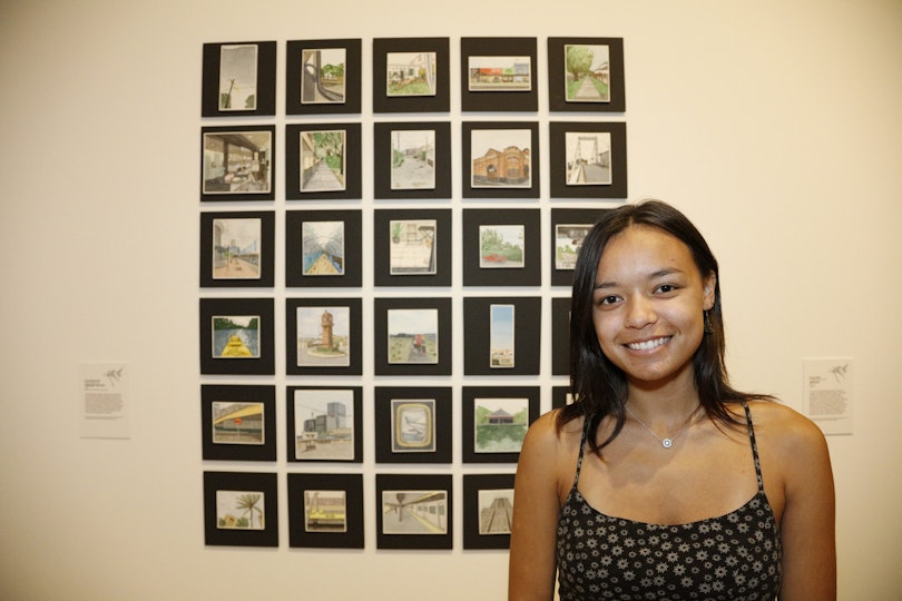 A person stands next to 30 images on a wall