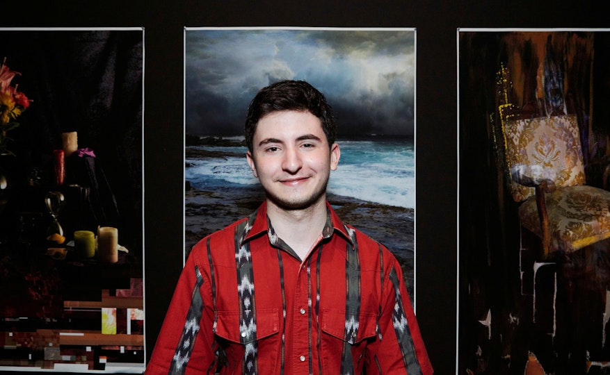A person stands in front of three large images on a wall