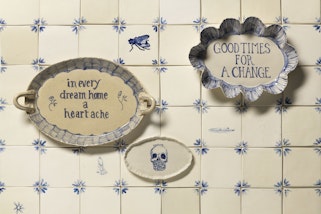 Square ceramic titles on which two ceramic oval discs read 'Chaos reigns' and 'In every dream home a heartache'