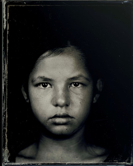 A black-and-white photography of the head, neck and upper shoulders of a young person