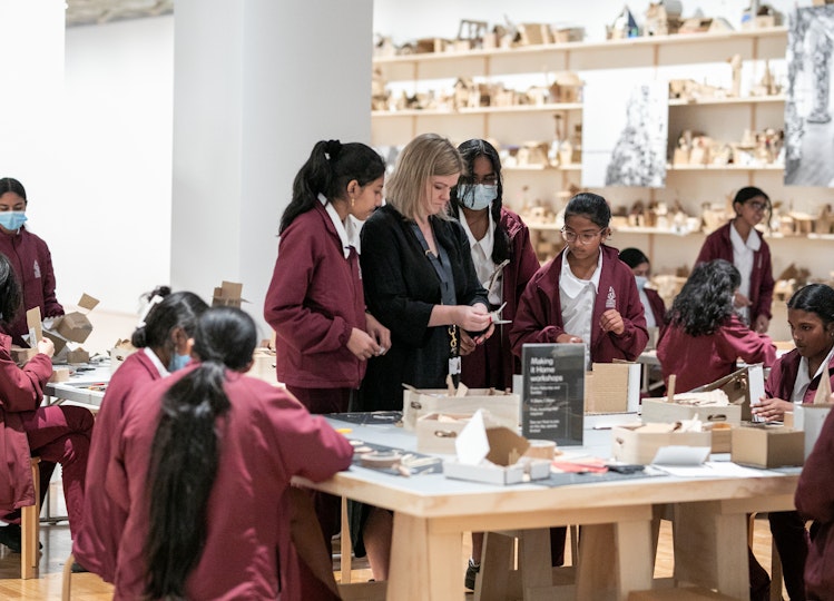 Students in uniform around tables with art-making materials