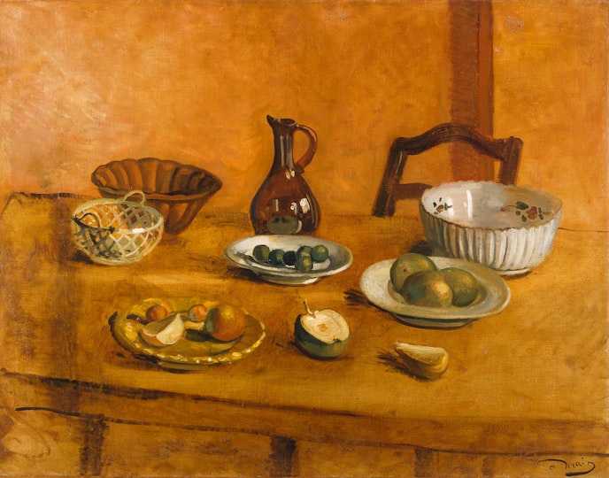 A chair at a table on which there are a jug, bowls, dishes and fruit