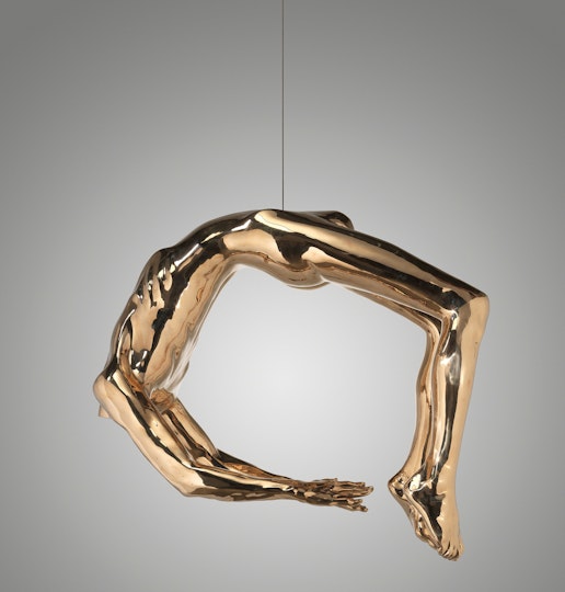 A suspended sculpture of a gold arched body