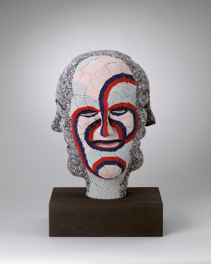 A textile sculpture of a head with four faces