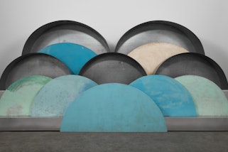 A sculpture of overlapping semi-circular shapes in shades of blue, grey, green and yellow