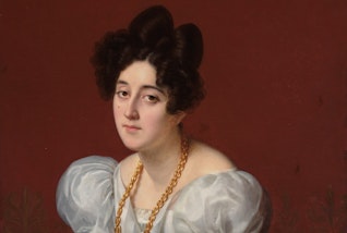 A person with dark hair piled high on their head, wearing a thick gold chain and white puffy sleeved clothing