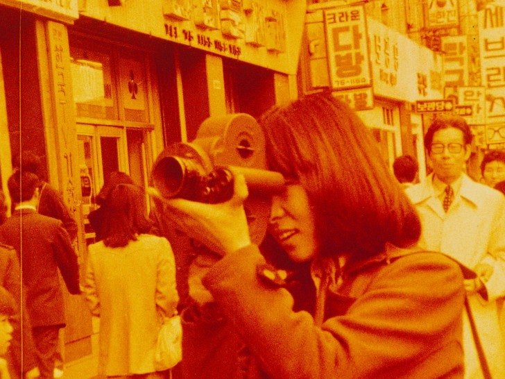 A person with a film camera in a busy city street