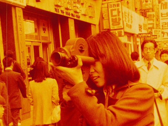 A person with a film camera in a busy city street