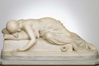 A marble sculpture of a person lying sideways and draped over a rectangular object