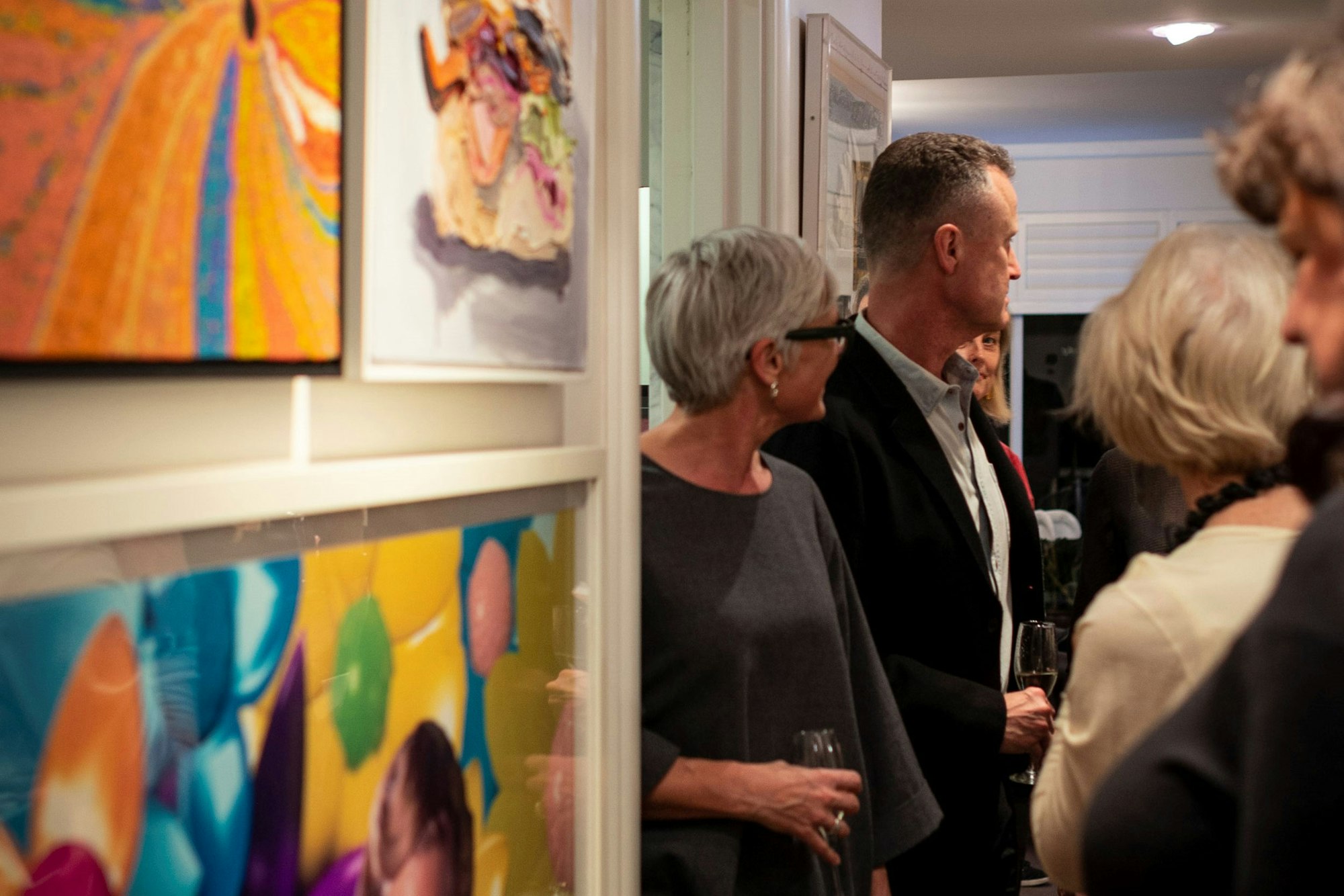 A group of people stand next to a wall with densely hung artworks