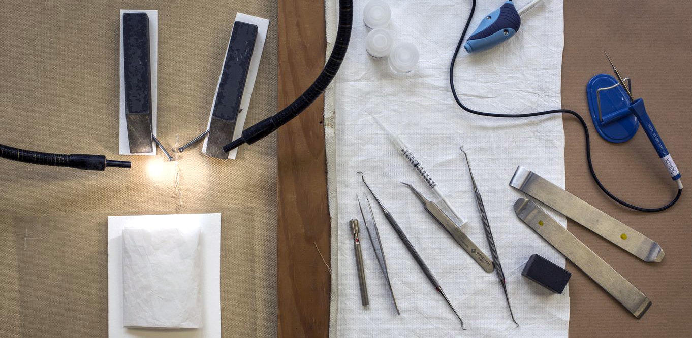 Various pieces of equipment used by art conservators lie on a worktop