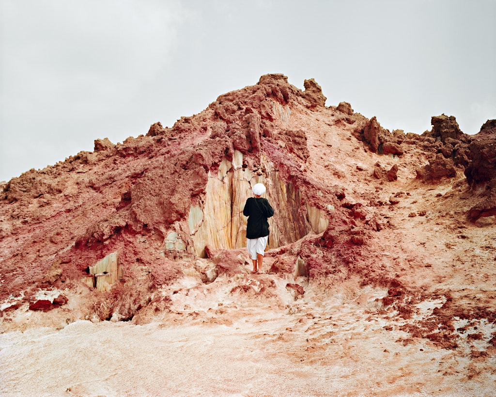 A person walks into a crevice in a sandy, rocky hill
