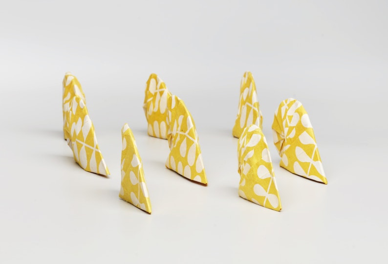 Several yellow-and-white patterned, shell-like origami shapes