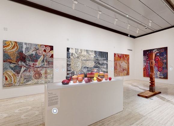 A room of large paintings and sculptures with virtual tags in grey circles appearing on the artwork labels.