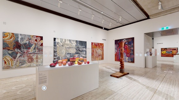 A room of large paintings and sculptures with virtual tags in grey circles appearing on the artwork labels.