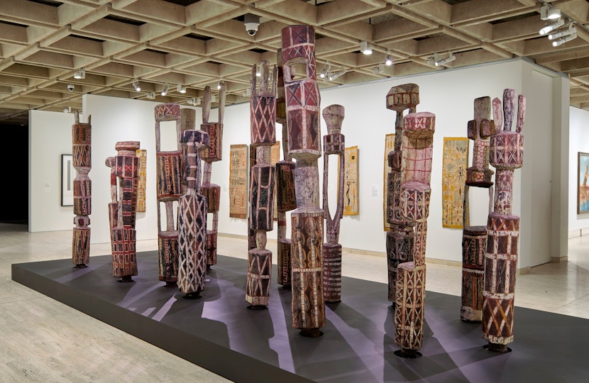 A group of vertical poles of varying shapes and heights, painted with varying patterns