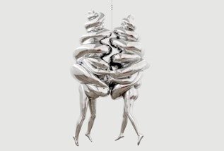 Two suspended and joined silver figures, each with legs and arms emerging from a spiral form
