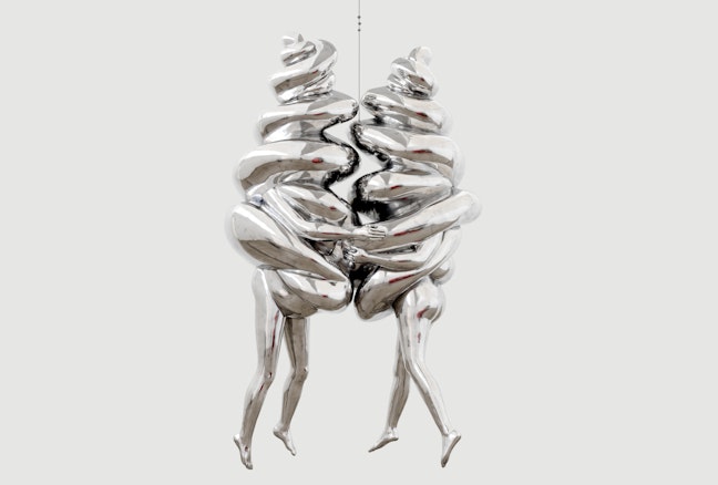 Two suspended and joined silver figures, each with legs and arms emerging from a spiral form